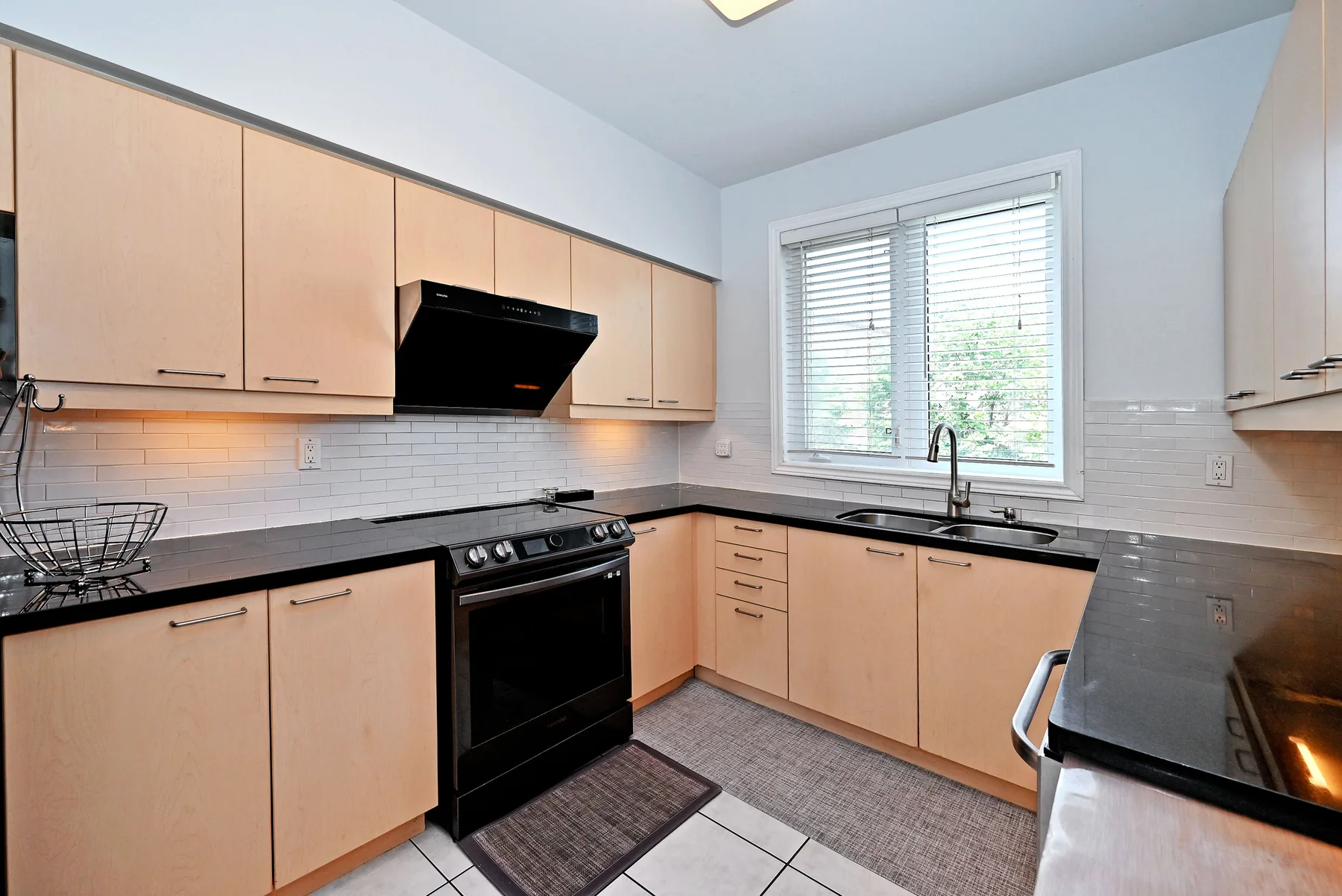 Kitchen with wood cabinetry, dark counters and stainless steel appliances